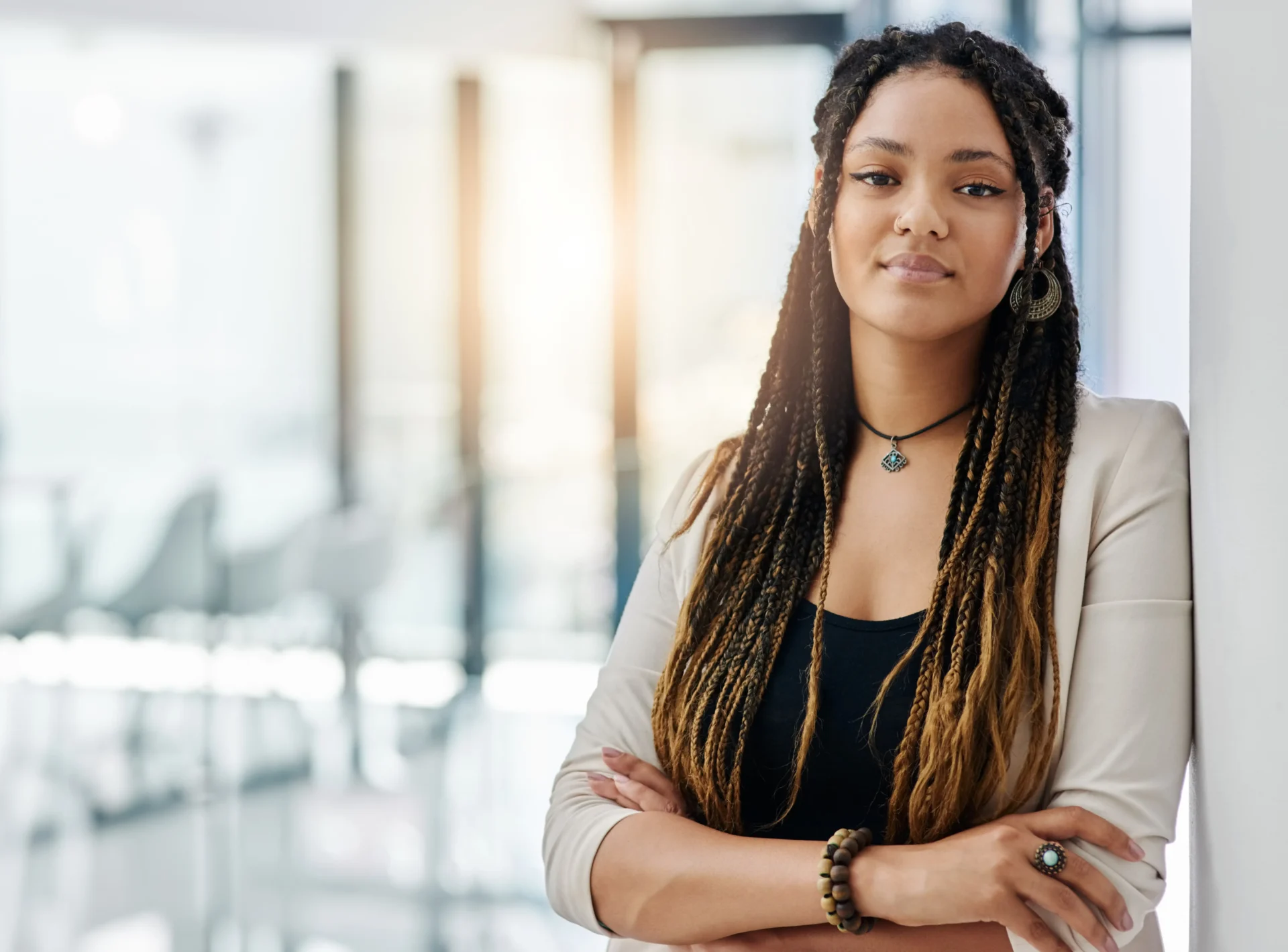 Woman standing with arms folded on wall in office space